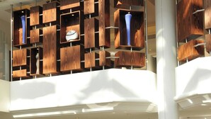 A modern lobby with a curved white sofa, a black chair, and a wooden wall with shelves.