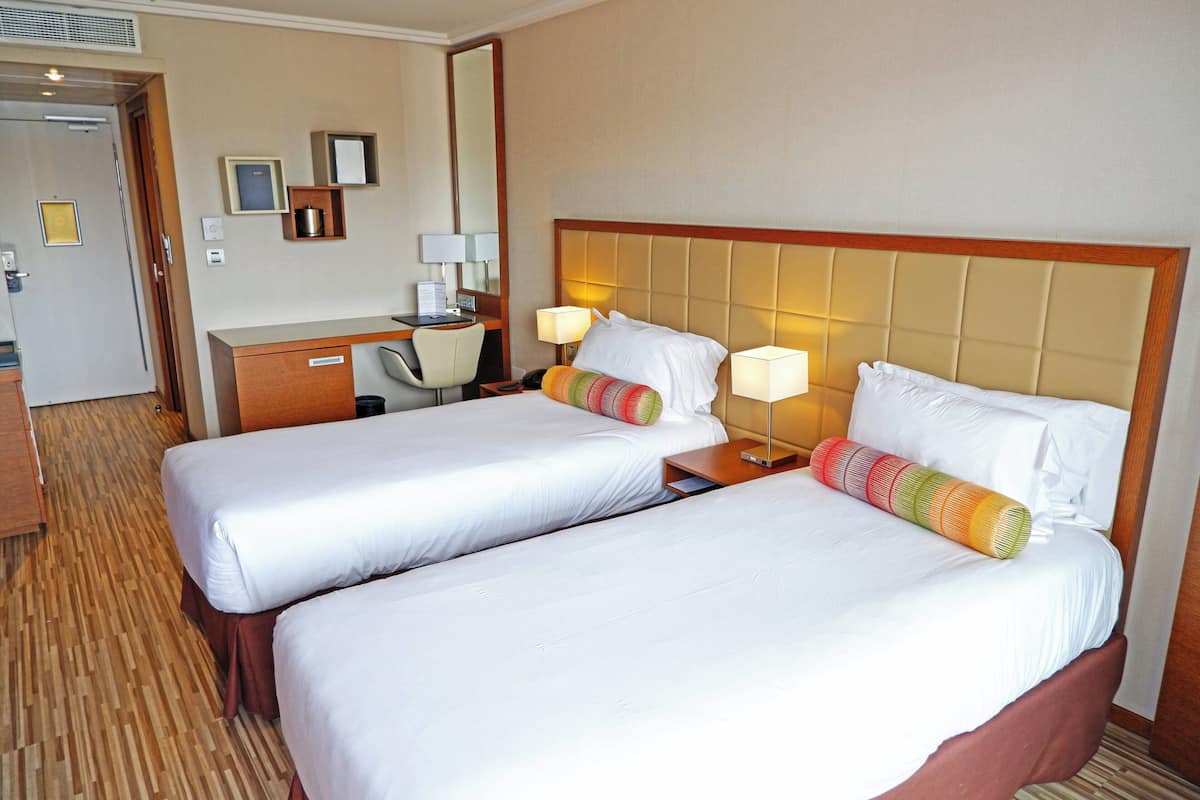 Ein Hotelzimmer mit zwei Betten, einem Schreibtisch und einem Stuhl.