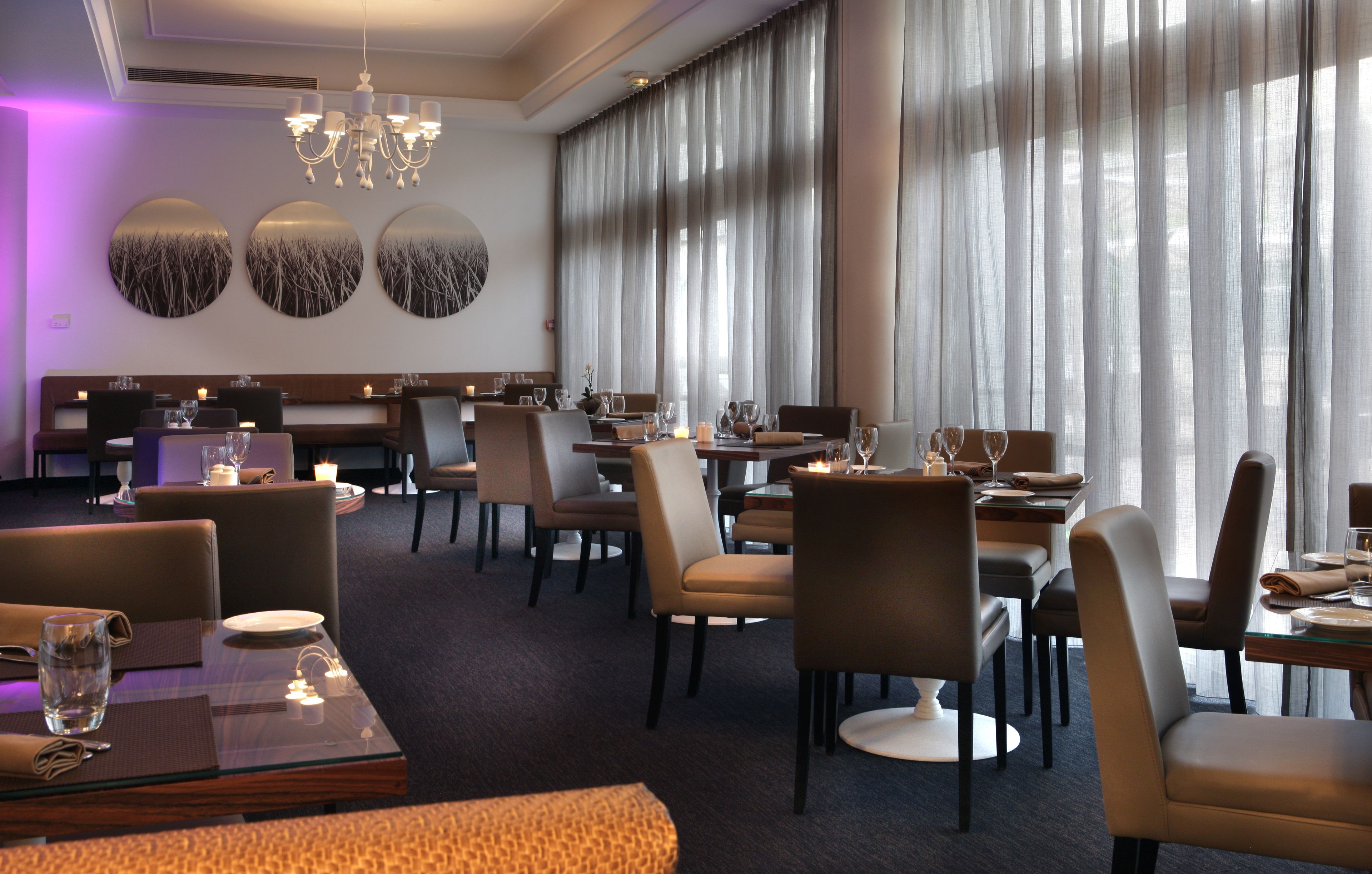 A restaurant with round tables, chairs, and a chandelier.
