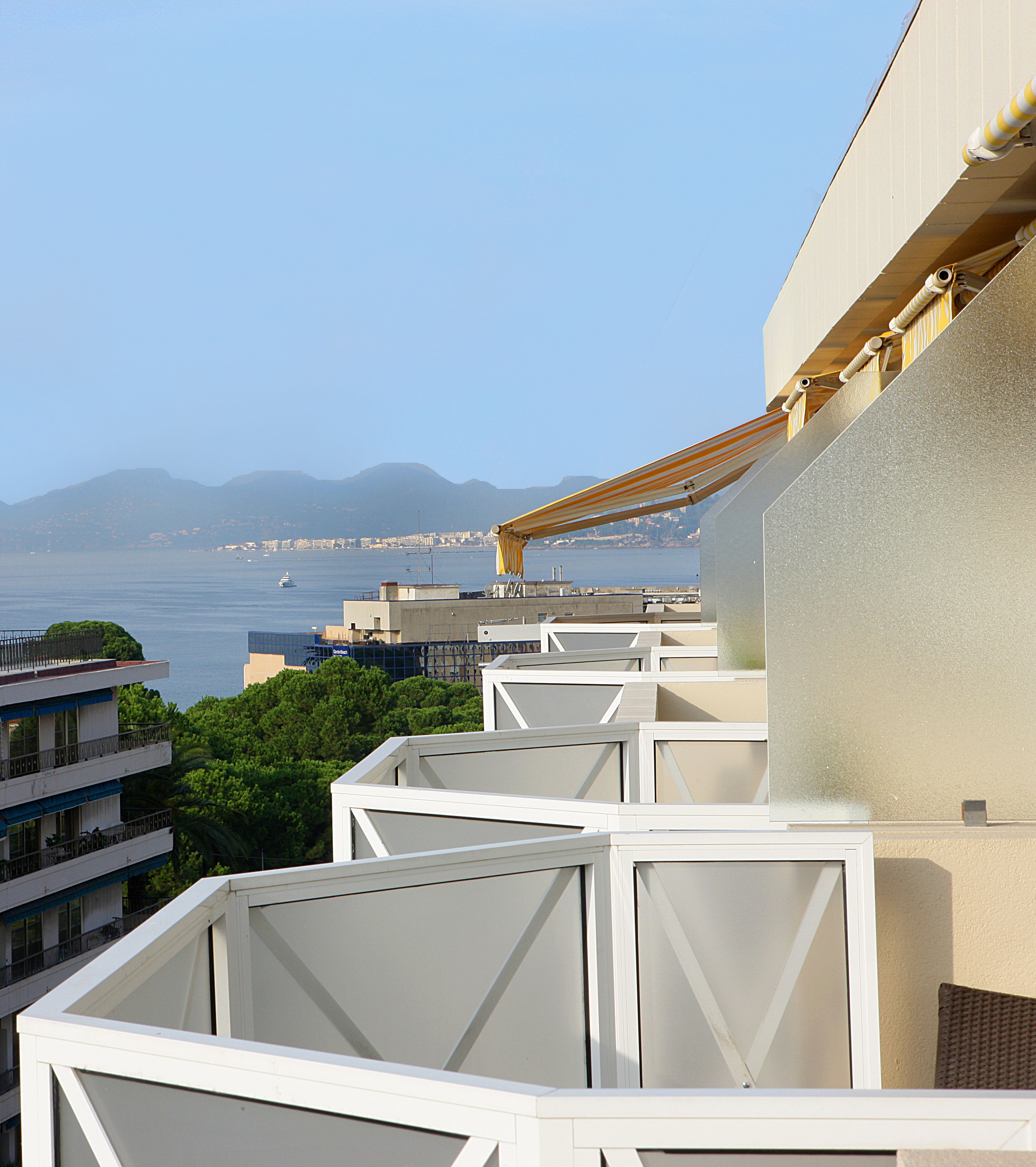 A balcony with a view of the sea and distant mountains.