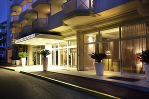 A hotel entrance with a sign reading 'AC HOTEL AMBASSADEUR,' large potted plants, and a glass door entrance. - AC Hotel by Marriott Ambassadeur Antibes - Juan Les Pins (Antibes)