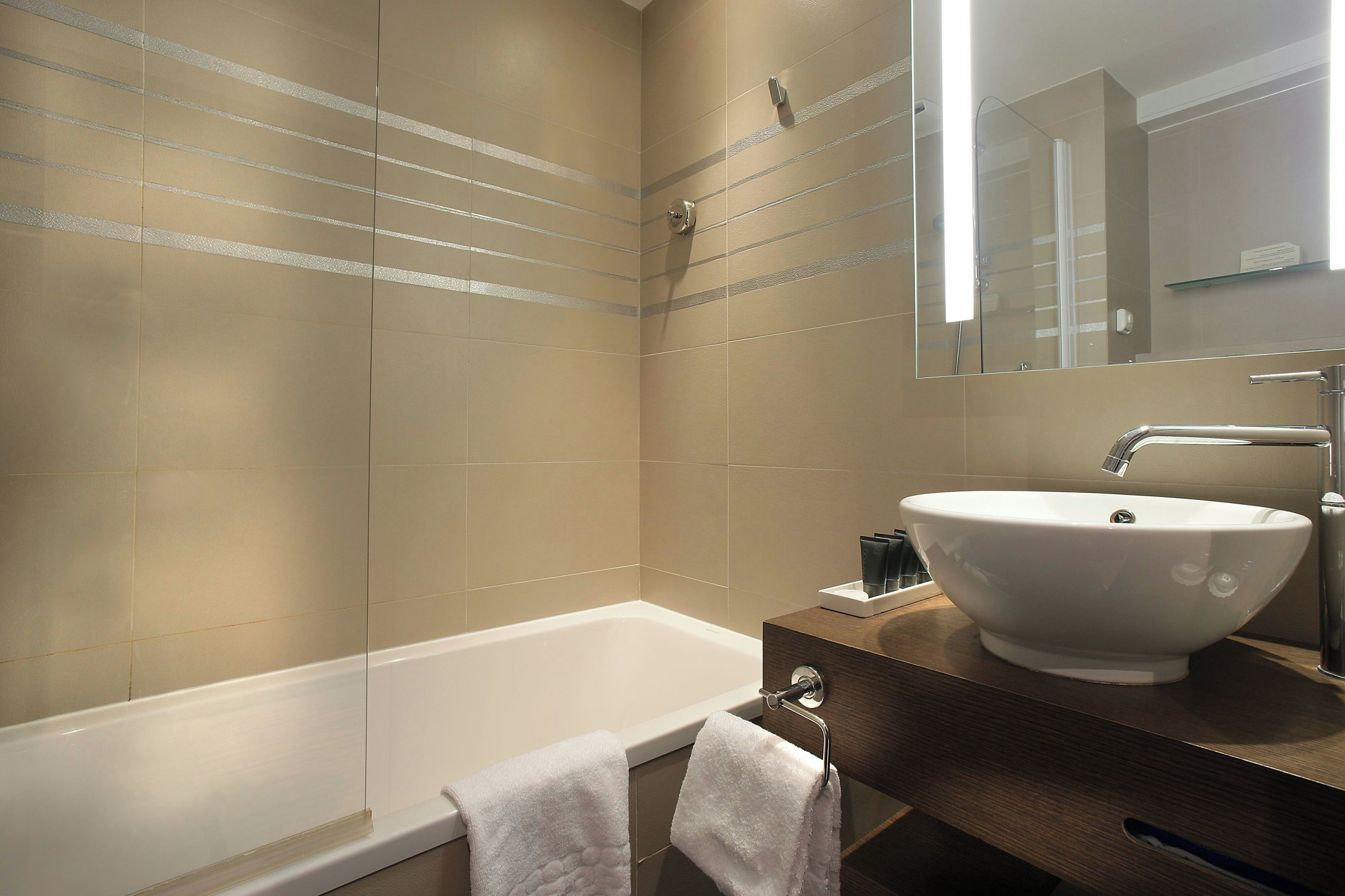 Un baño moderno con bañera, un lavamanos grande y un espejo.