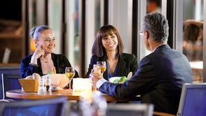 A dining table with a basket, salt and pepper shakers, and glasses of wine. - Novotel Paris Saclay (Saclay)