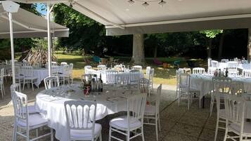 An outdoor event space with round tables, white chairs, and string lights.