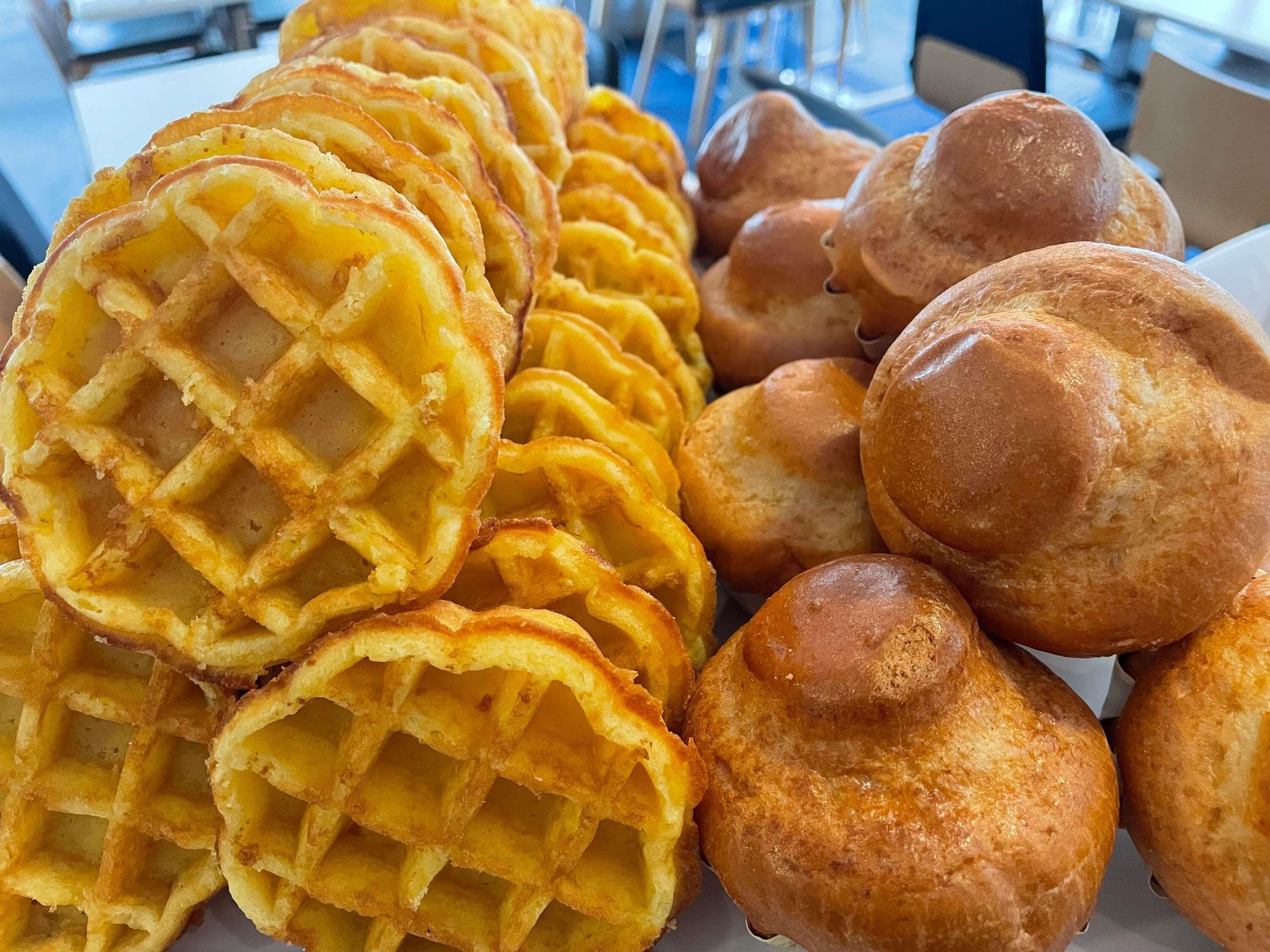 Variedad de gofres y panes redondos pequeños sobre una mesa.