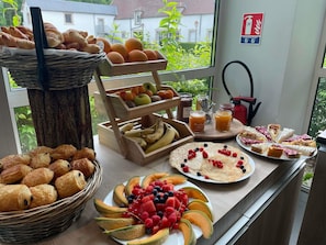 A breakfast buffet with pastries, fruits, and spreads.