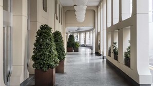 A long corridor with a series of spherical ceiling lights, large windows, and potted plants. - Hilton Garden Inn Padova City Centre (Padova)
