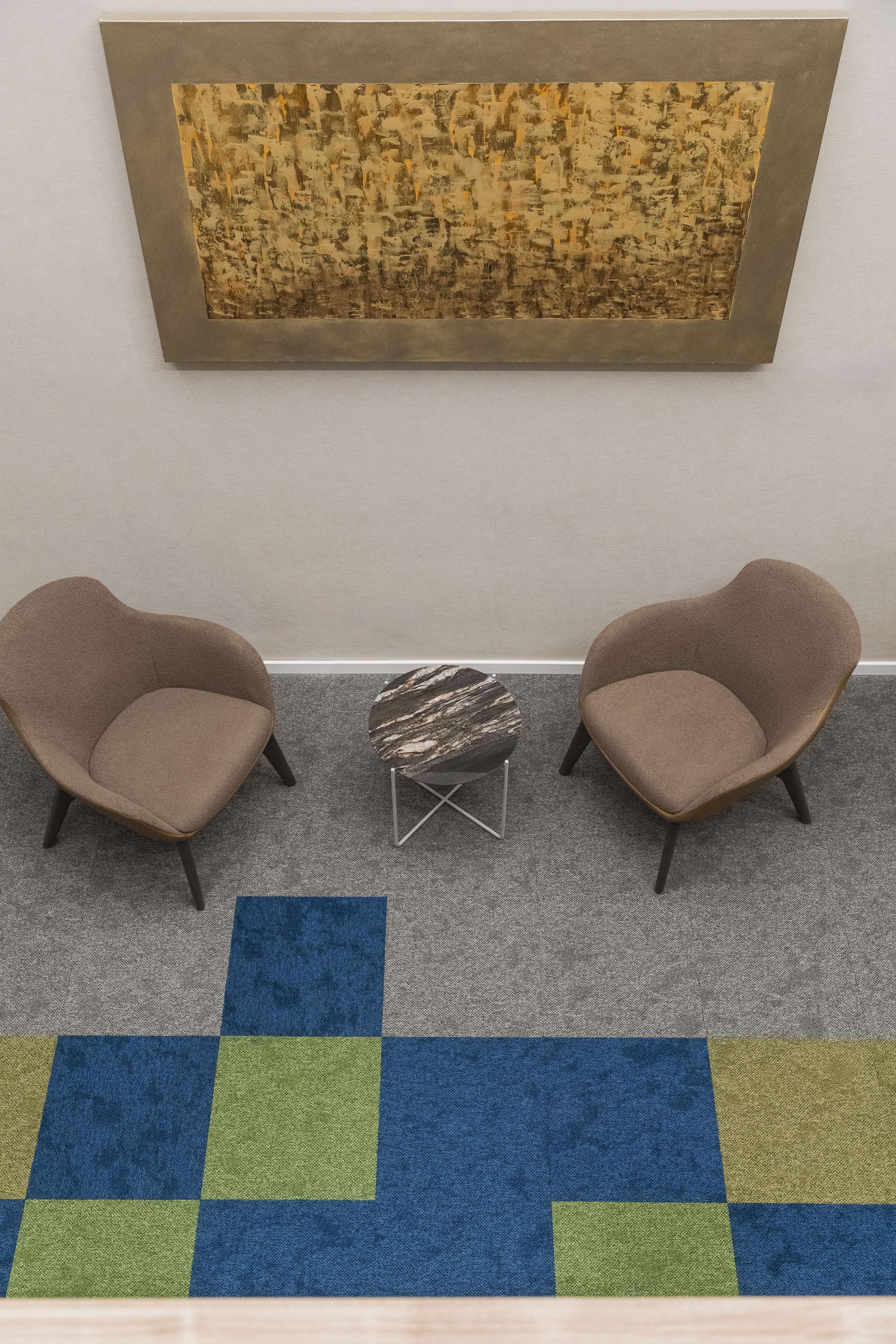 A room with two armchairs, a small table, and a large abstract painting on the wall.
