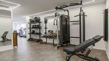 Un gimnasio con equipo de ejercicio, una banca y un espejo.