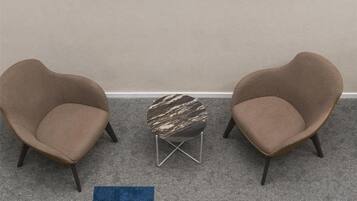 Ein Zimmer mit zwei Sesseln, einem kleinen Couchtisch und einem großen, abstrakten Gemälde an der Wand.