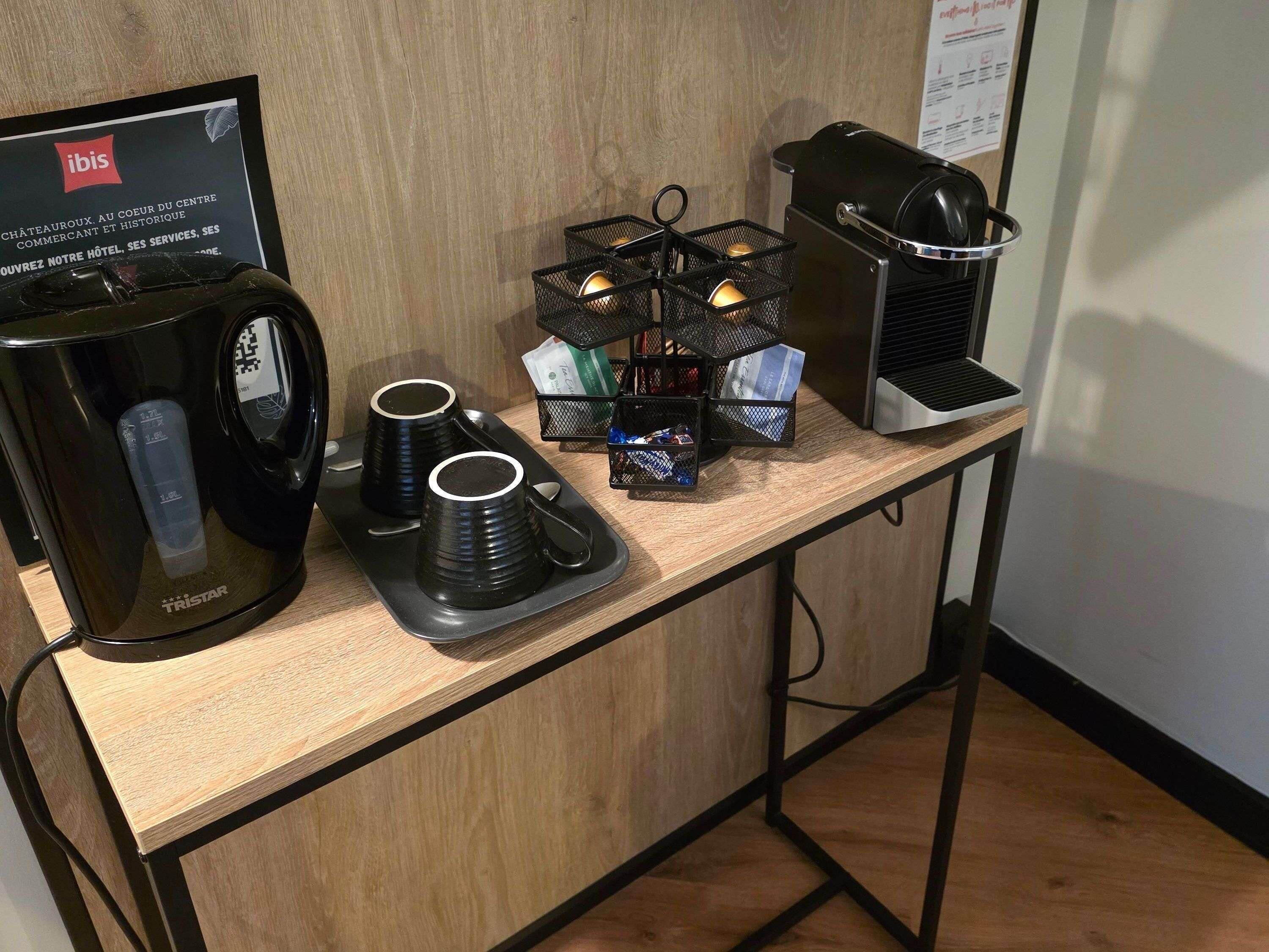Uma estação de café com cafeteira, xícaras e uma bandeja.