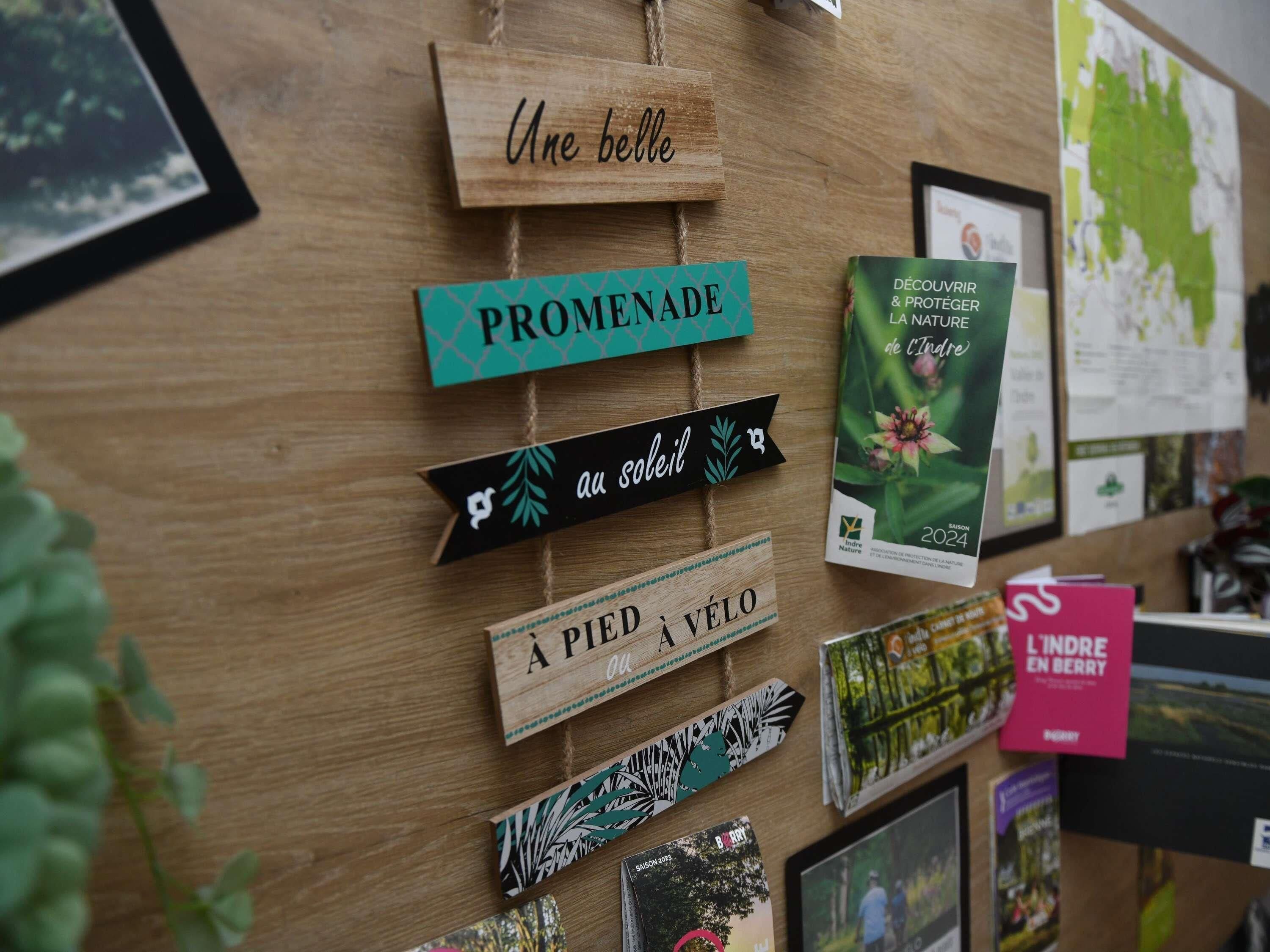 Pared de madera con varios carteles y portadas de libros, incluyendo 'Une belle', 'PROMENADE', 'au soleil', 'A pied à vélo' y 'L'INDRE EN BERRY'.