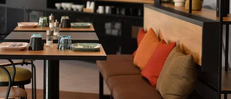Un comedor moderno con una mesa de madera, sillas y un banco con cojines.