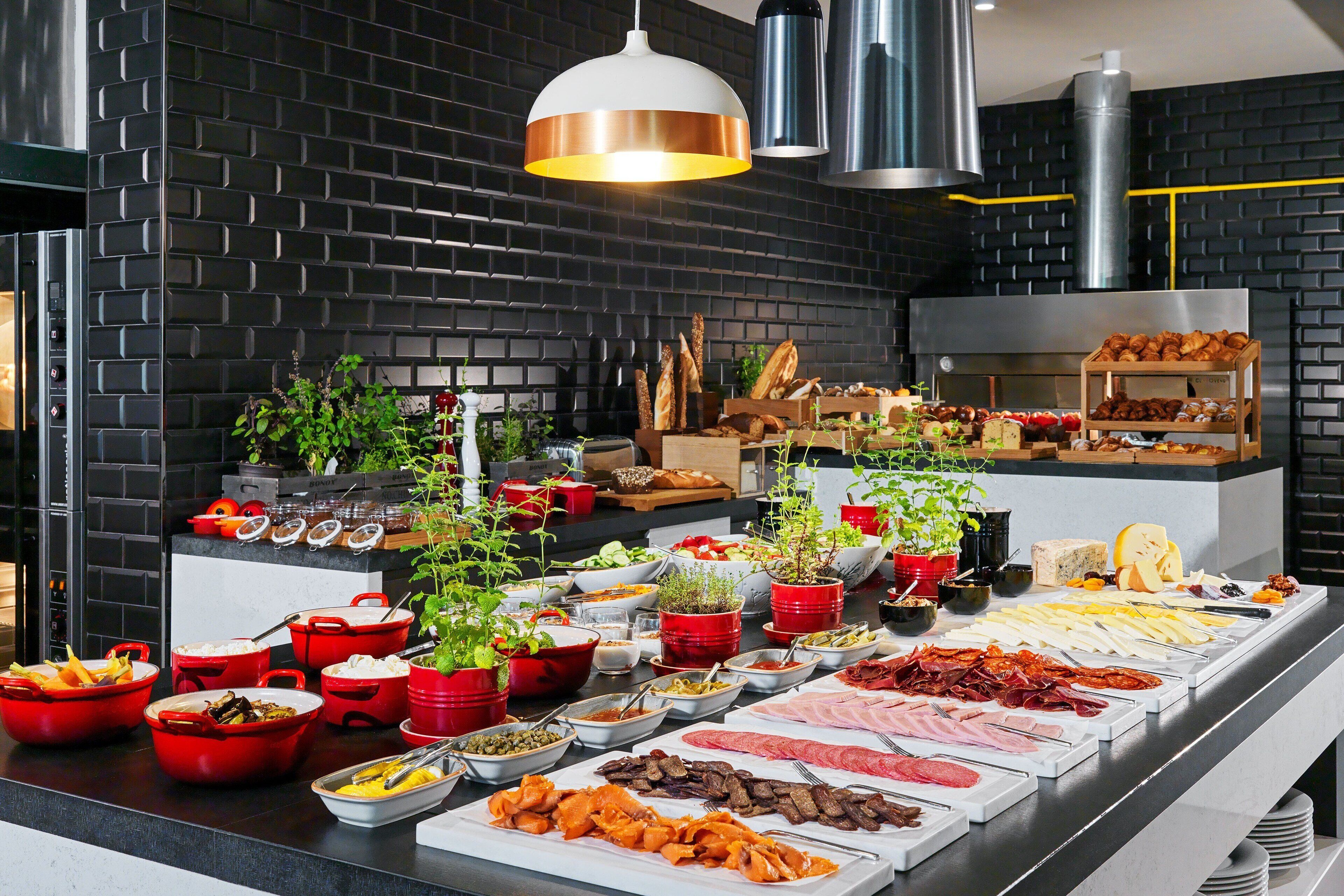 A buffet with various food items and a brick wall background.