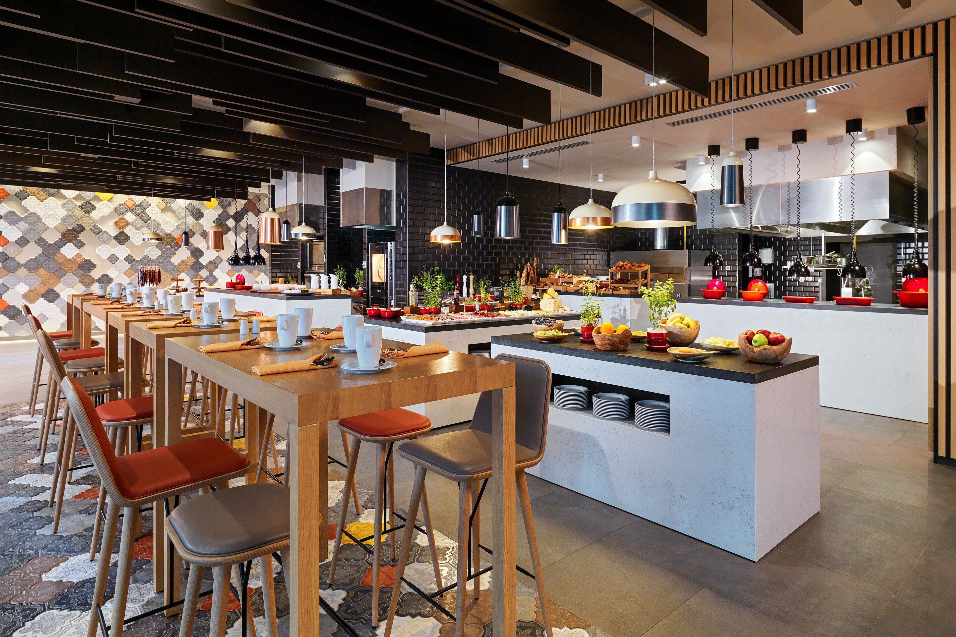 A modern kitchen with a central island, bar stools, and a patterned backsplash.