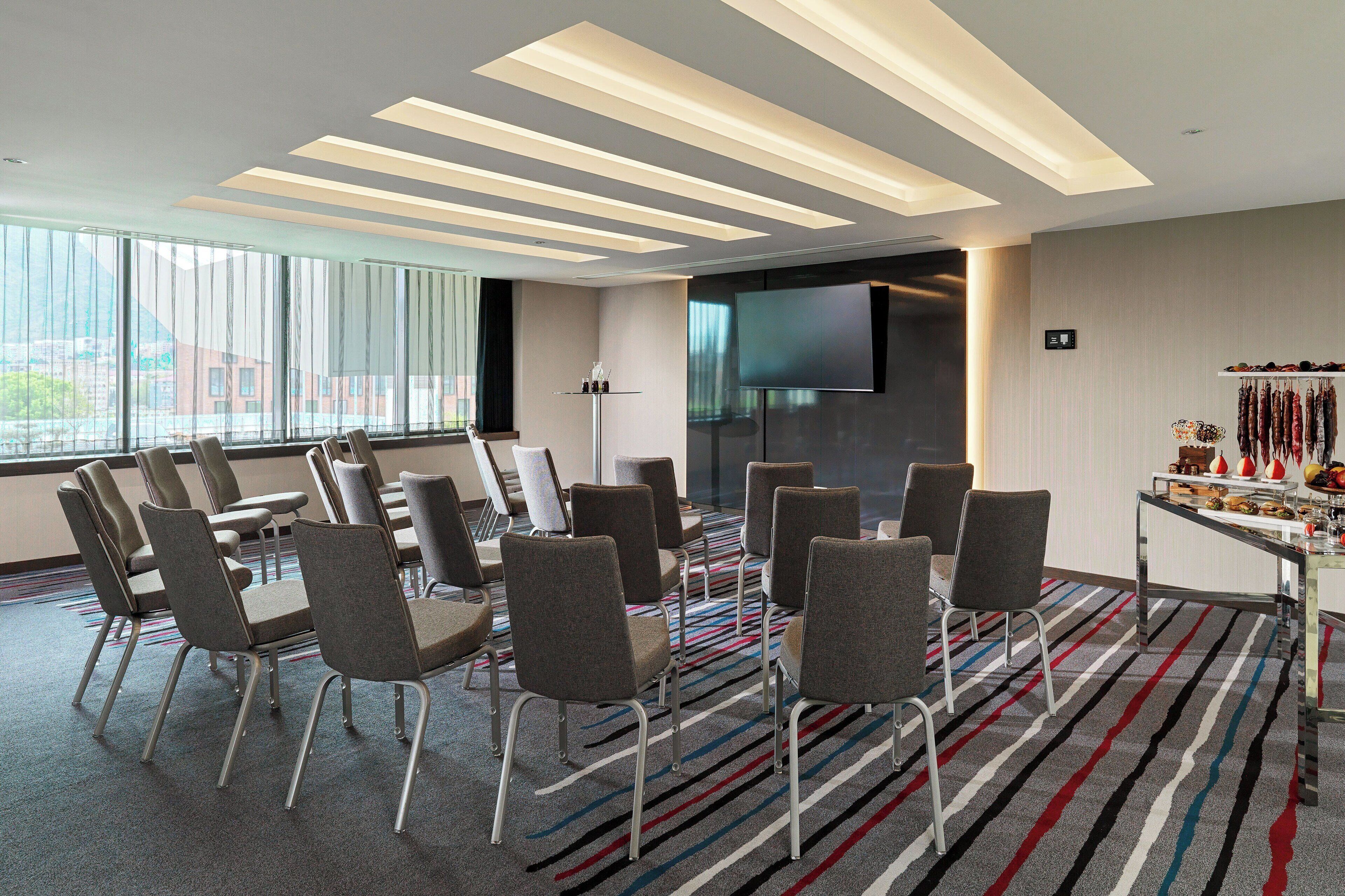 A conference room with a large screen, multiple chairs, and a buffet table.