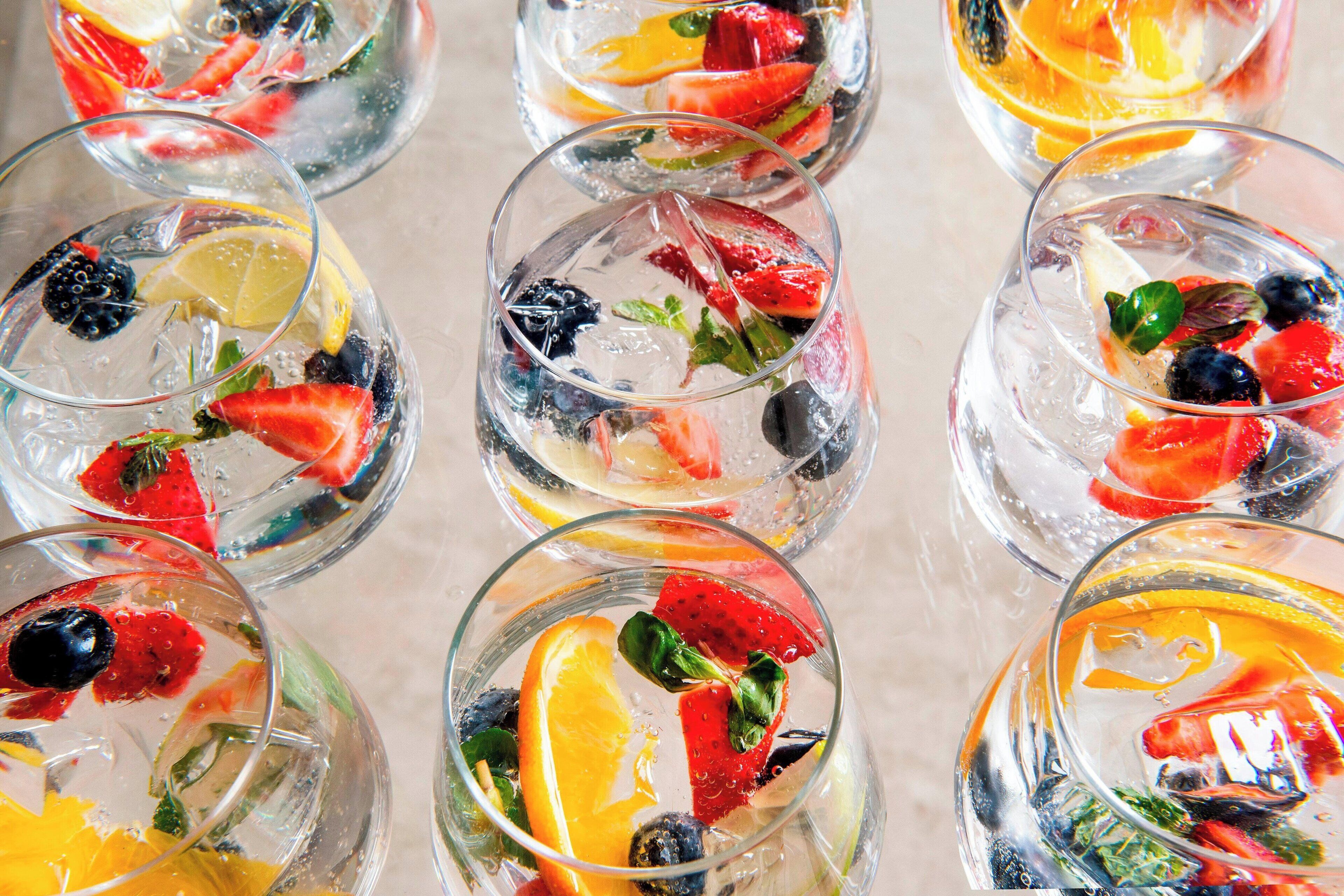 Varios vasos de agua con diferentes frutas y hojas de menta.