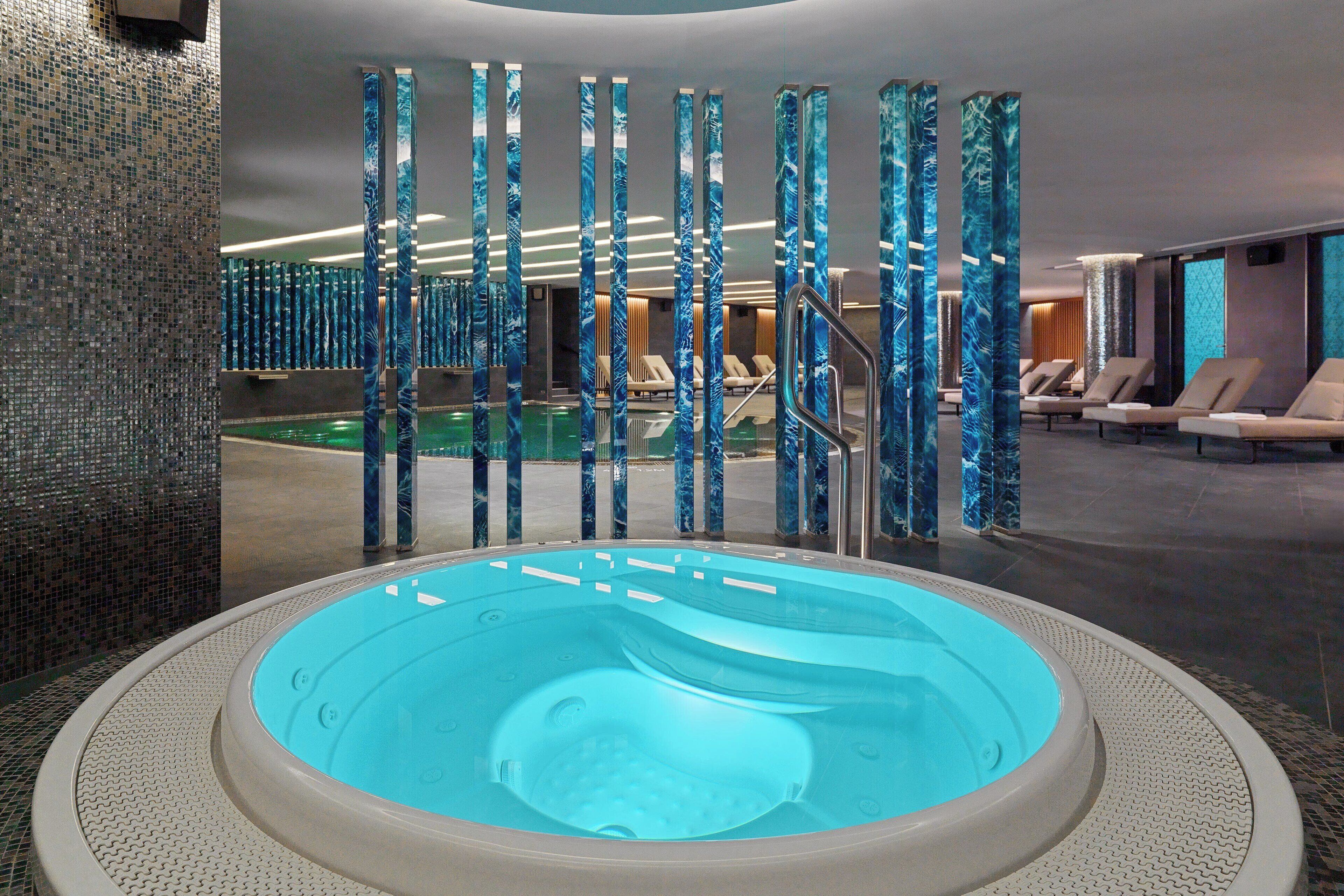 Un espace bien-être comprenant un jacuzzi, des chaises longues et une piscine.