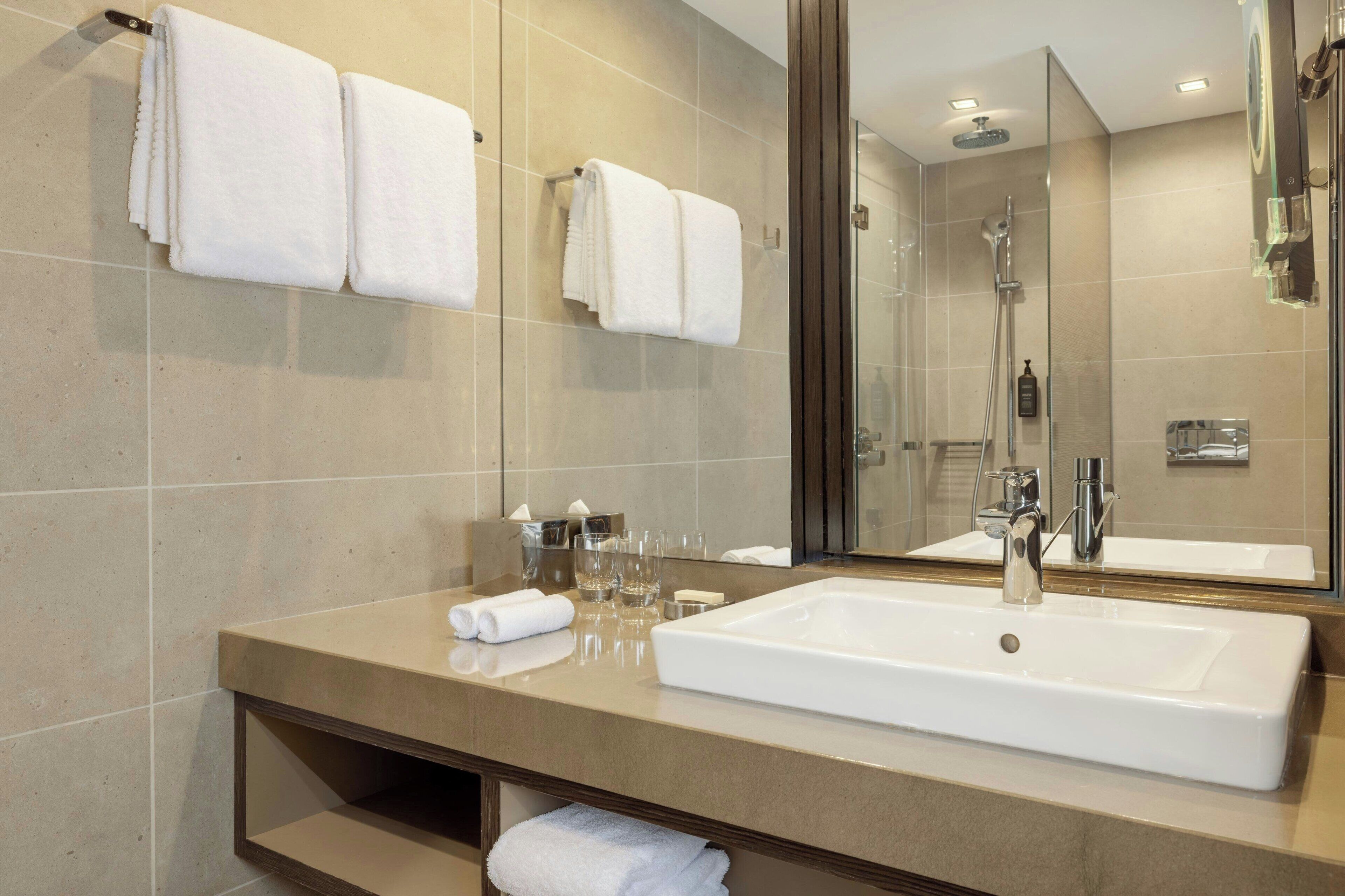 Un baño moderno con un lavamanos grande, espejo y ducha.