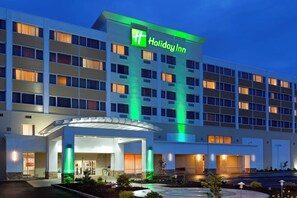 A Holiday Inn hotel with a modern design, featuring a prominent green and white sign, multiple floors with evenly spaced windows, and a well-lit entrance. - Holiday Inn Clark - Newark Area by IHG (Clark)