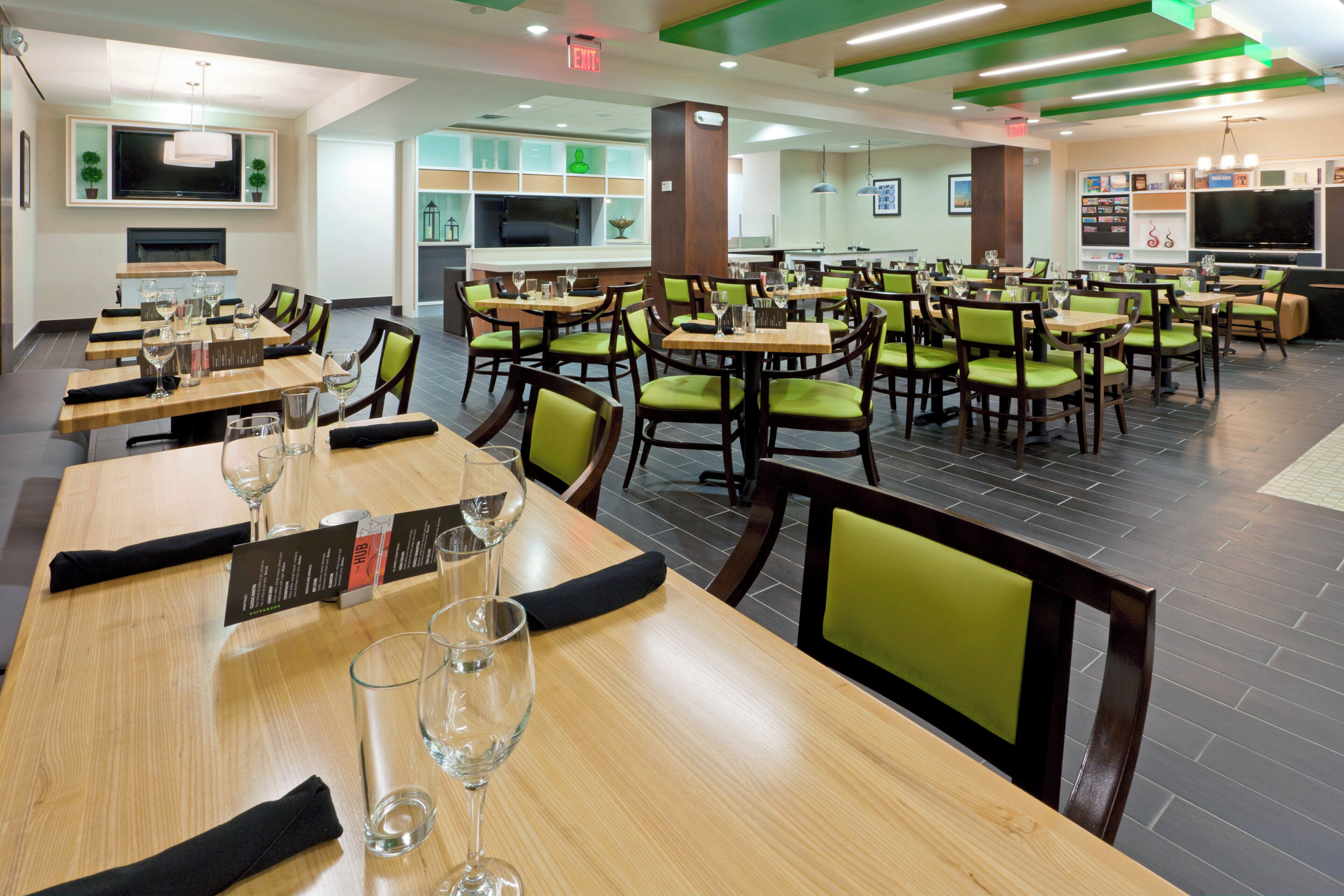 A restaurant with multiple dining tables, chairs, and empty wine glasses.