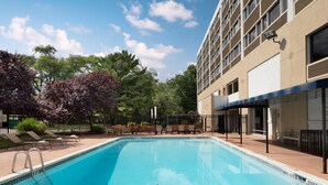 Una piscina con sillas de descanso y un edificio con varias ventanas.