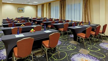 A conference room with multiple tables, chairs, and a carpeted floor.