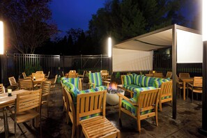 An outdoor patio area with wooden furniture, a fire pit, and a covered seating area. - Holiday Inn Clark - Newark Area by IHG (Clark)