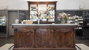A bar area with a wooden counter, a glass display case with bottles, and a chalkboard menu. - Altstadt Hotel (Zürich)