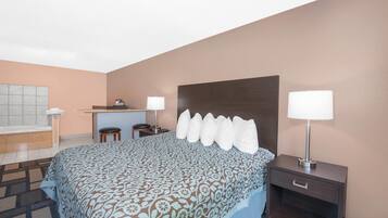 Quarto de hotel com uma cama grande, uma escrivaninha, duas cadeiras, uma mesinha e duas luminárias de cabeceira.