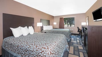 A hotel room with two beds, a desk, a chair, a TV, and a window with curtains.