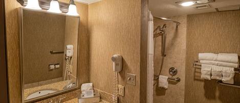 Un baño con lavamanos, espejo y ducha.
