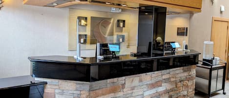 A reception desk with a stone base and a black countertop, equipped with a computer and a telephone.