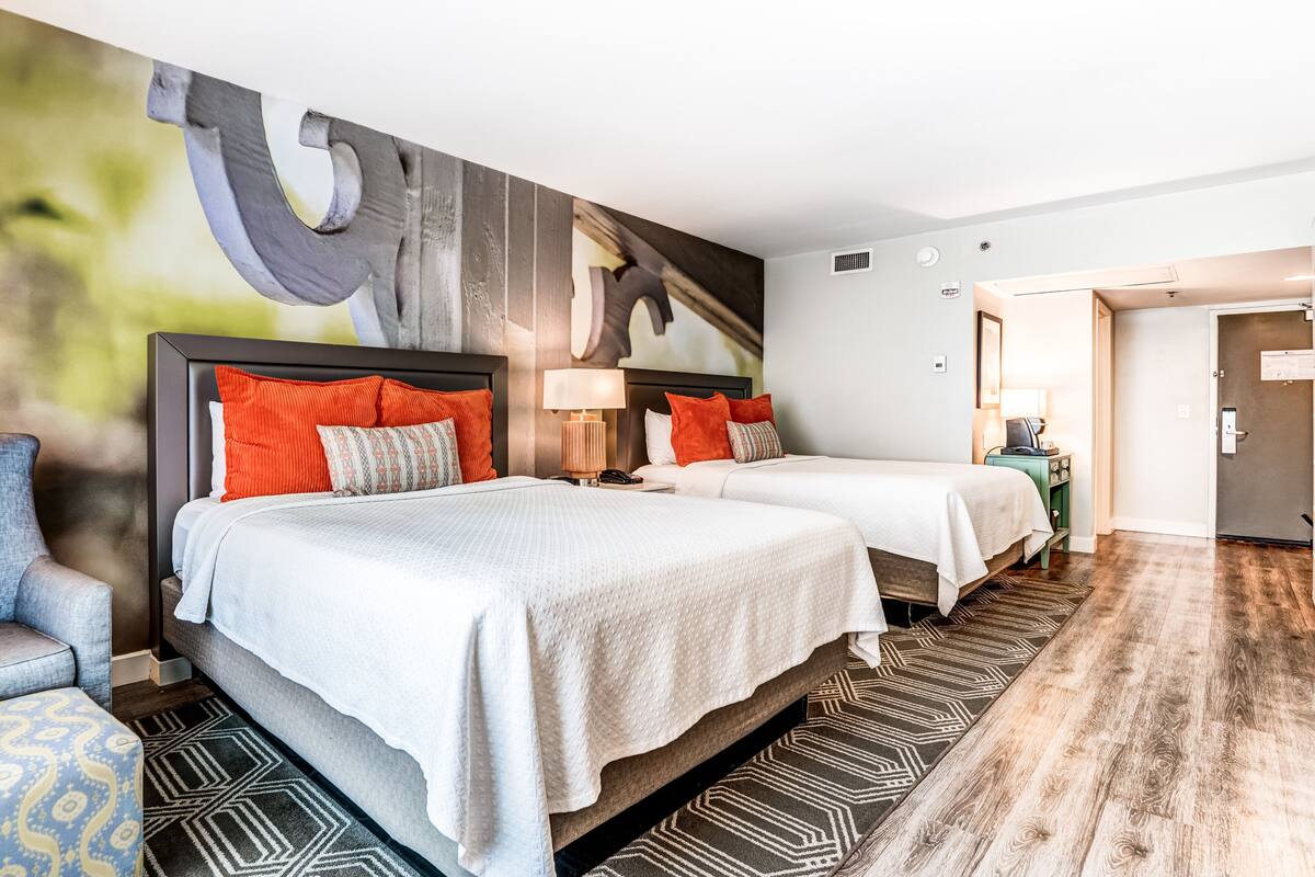 Una habitación de hotel con dos camas, un cuadro abstracto grande en la pared y una alfombra estampada.