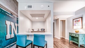 A modern kitchen with a white island, two blue bar stools, and a teal sideboard. - Hotel Indigo Atlanta-Vinings Ballpark Area by IHG (Atlanta)