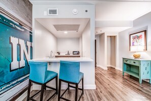 A modern kitchen with a white island, two blue bar stools, and a teal sideboard. - Hotel Indigo Atlanta-Vinings Ballpark Area by IHG (Atlanta)