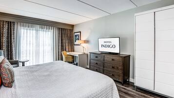 A hotel room with a large bed, a desk, a chair, a dresser, and a wardrobe.