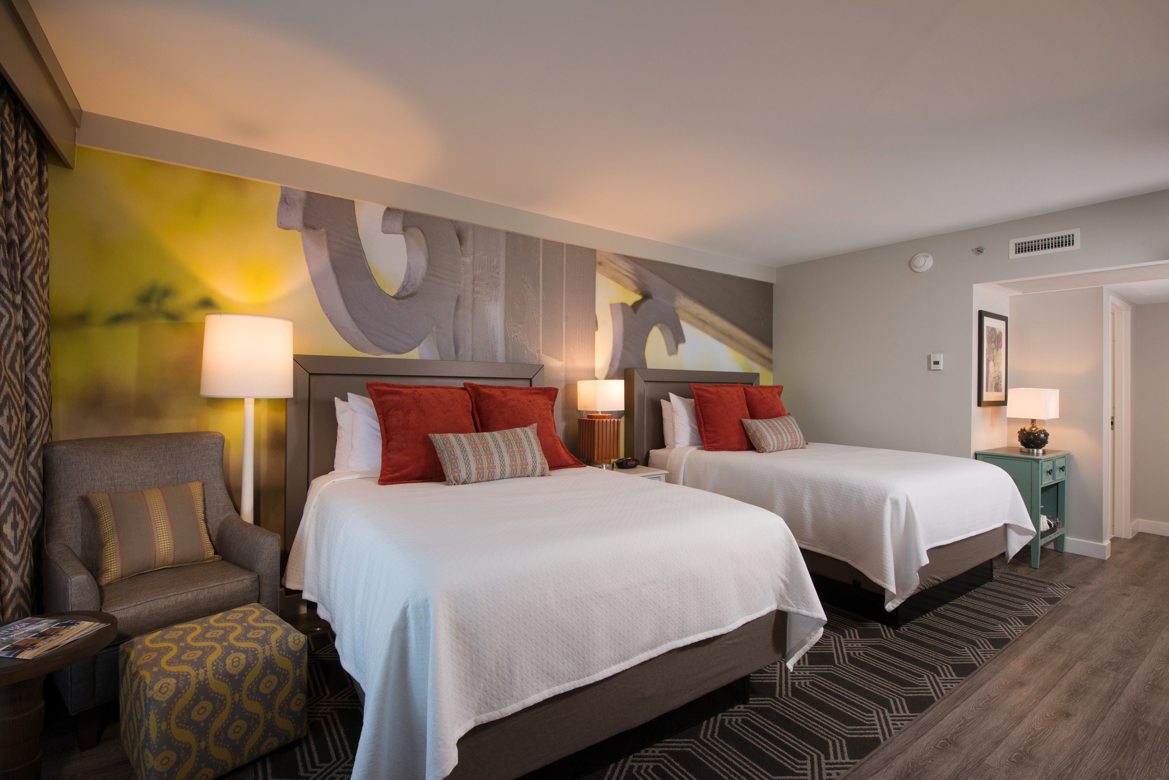 A hotel room with two beds, a sofa, a small table, and a patterned rug.