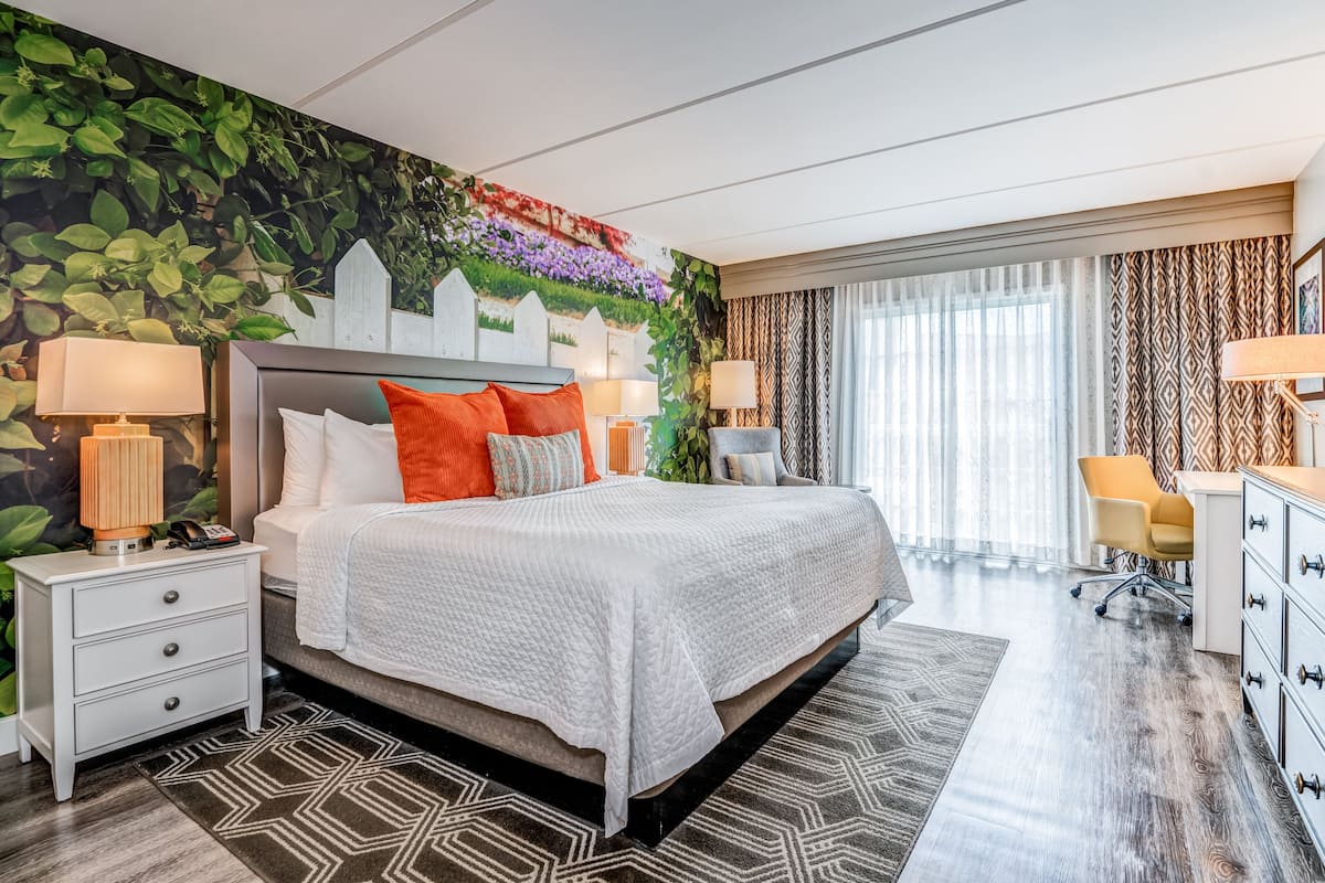 Una habitación de hotel moderna con una cama grande, dos mesitas de noche, un escritorio y una silla.