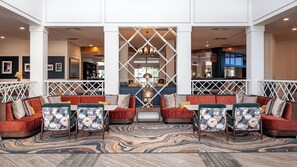 A lobby with a central seating area, a patterned rug, and a decorative partition. - Hotel Indigo Atlanta-Vinings Ballpark Area by IHG (Atlanta)
