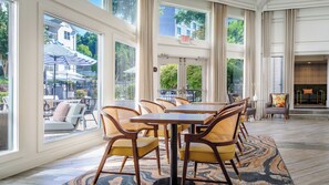 A spacious dining area with a large table and chairs, large windows with a view of the outside, and a separate seating area with a sofa and armchairs. - Hotel Indigo Atlanta-Vinings Ballpark Area by IHG (Atlanta)
