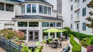 A two-story building with a bay window, a stone chimney, and a patio with outdoor seating. - Hotel Indigo Atlanta-Vinings Ballpark Area by IHG (Atlanta)