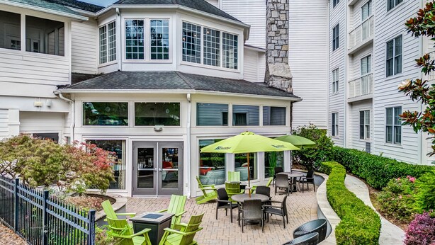 A two-story building with a bay window, a stone chimney, and a patio with outdoor seating. - Hotel Indigo Atlanta-Vinings Ballpark Area by IHG (Atlanta)