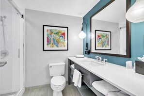 A modern bathroom with a toilet, sink, and shower. There are two framed artworks on the walls. - Hotel Indigo Atlanta-Vinings Ballpark Area by IHG (Atlanta)