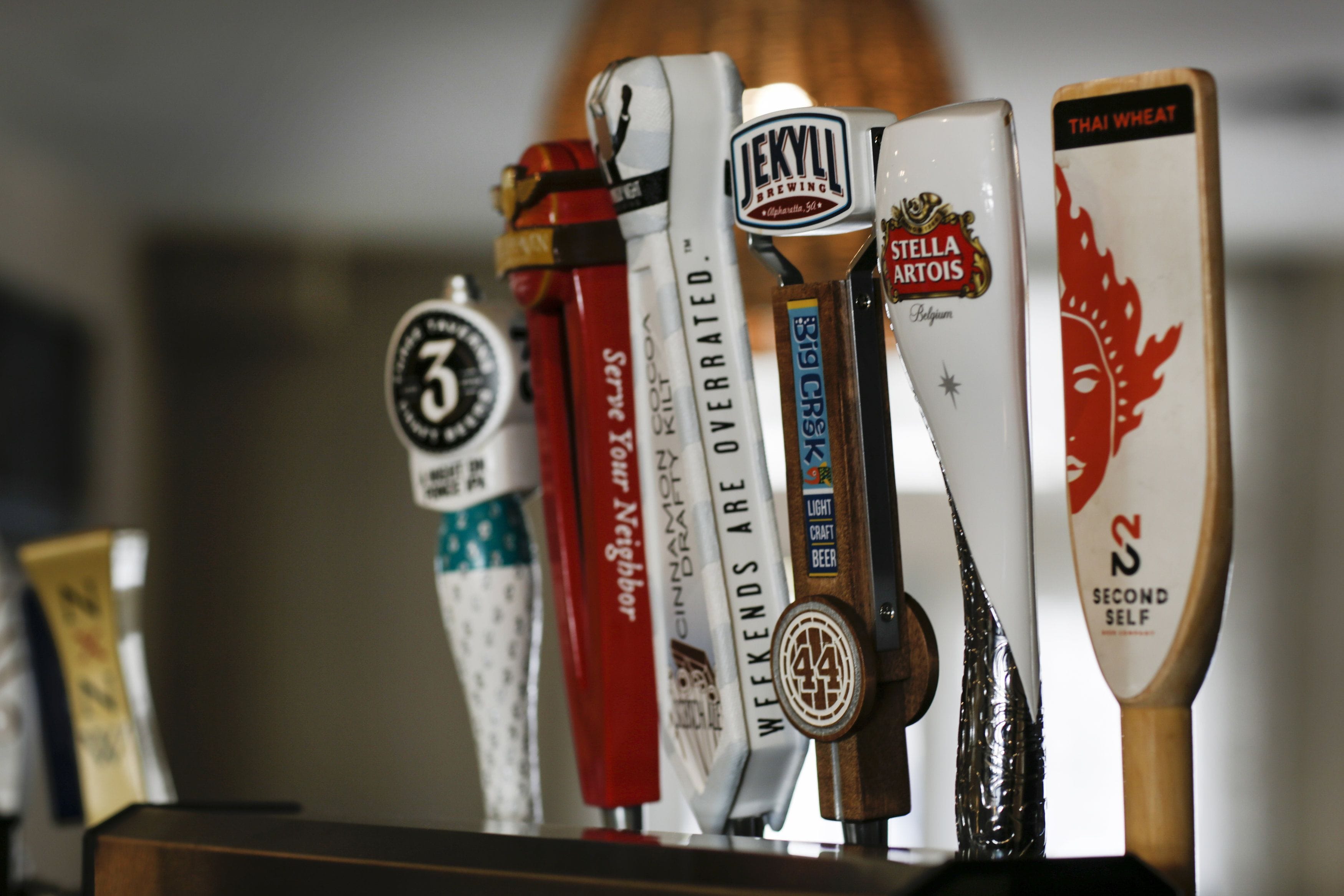 A row of beer taps with labels such as "Jekyll Brewing," "Stella Artois," and "Thai Wheat."
