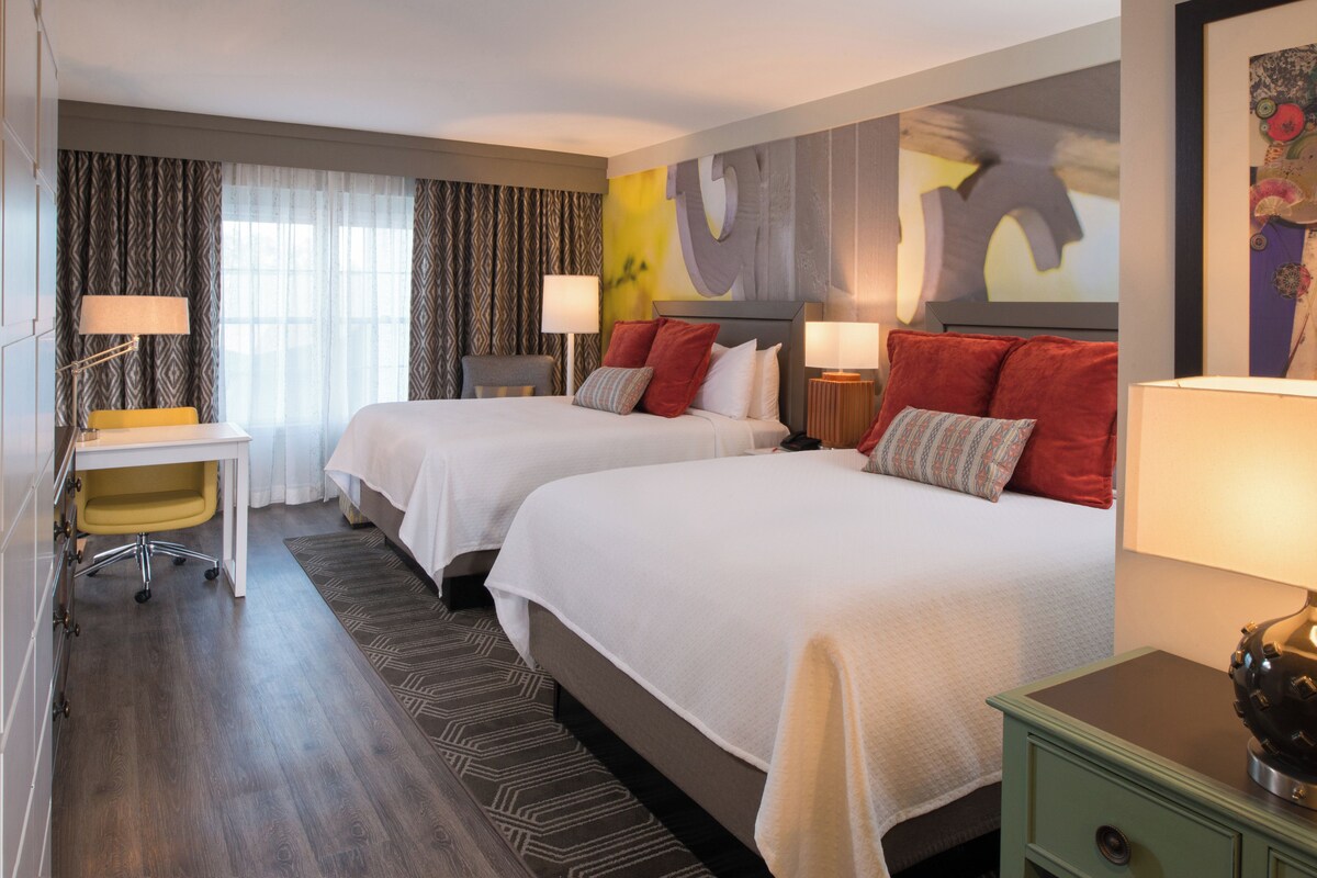 Una habitación de hotel con dos camas, un escritorio y una silla.