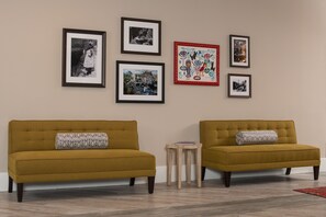 Two mustard-colored sofas with patterned cushions, a small wooden side table, and four framed artworks on the wall. - Hotel Indigo Atlanta-Vinings Ballpark Area by IHG (Atlanta)