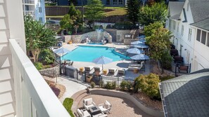 A rooftop pool with lounge chairs and umbrellas, surrounded by a stone wall and greenery. - Hotel Indigo Atlanta-Vinings Ballpark Area by IHG (Atlanta)