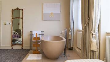 A bathroom with a large bathtub, a mirror, a towel rack, and a radiator.