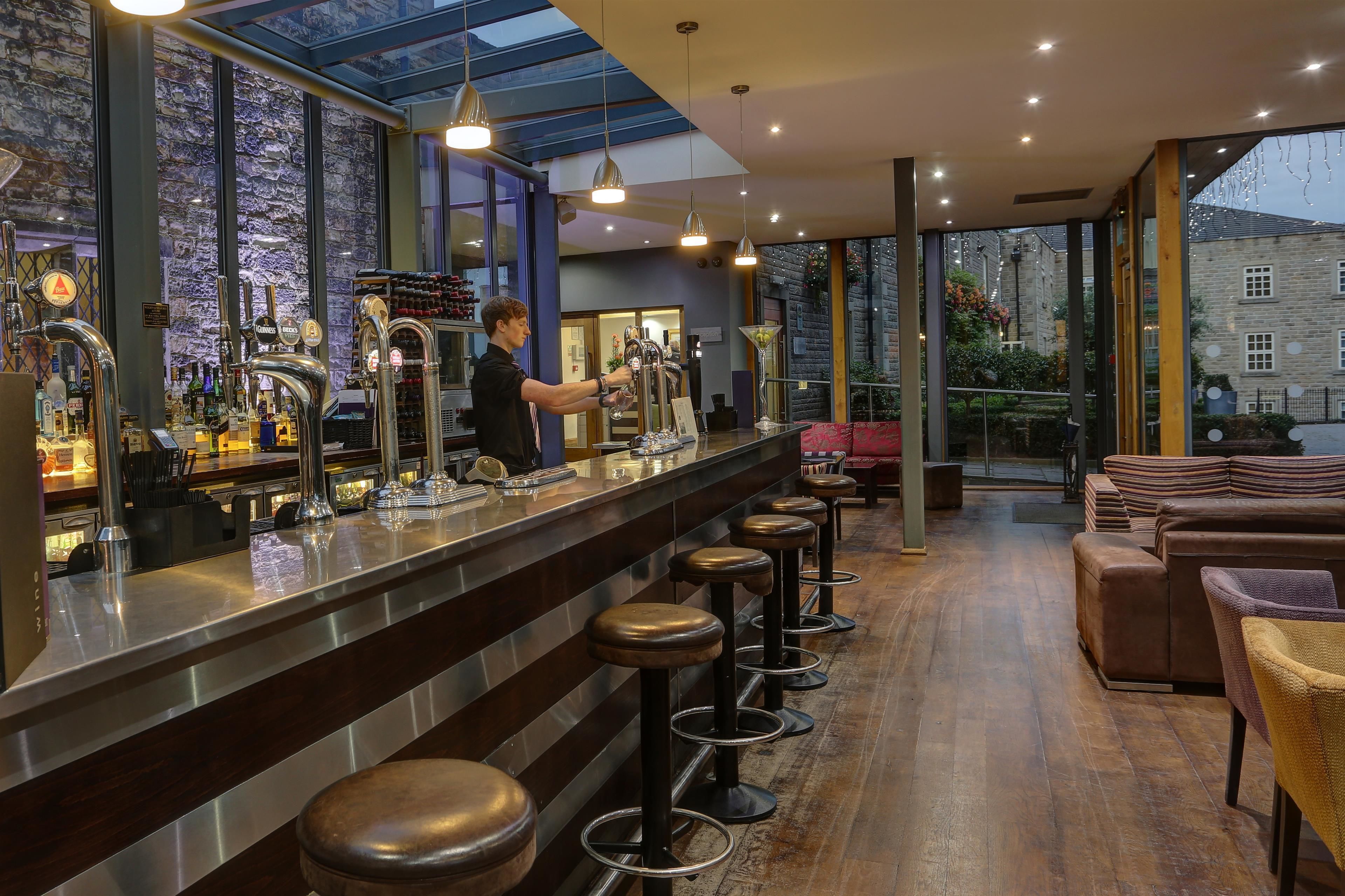 A bar area with a bartender, stools, and a view of the outside.